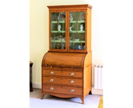 A late George III Hepplewhite satinwood cylinder bureau bookcase, the tulipwood banded cornice with arcaded frieze, the two g