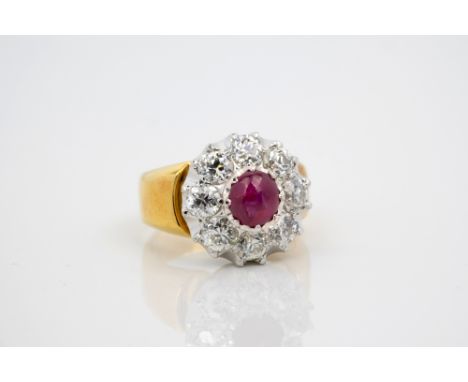 An 18ct two-colour gold, pink star sapphire and diamond cluster ring, the round cabochon sapphire crown-set above a border of