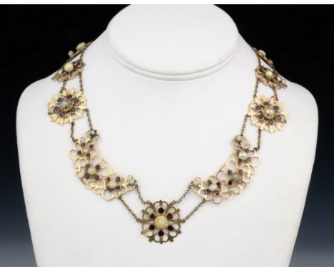 A Victorian 14ct rose gold, pearl and garnet necklace, with eleven floral style openwork motifs set with round cut garnets an