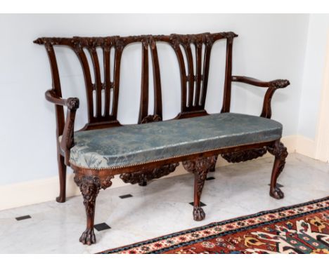 A George II carved mahogany double chairback settee in the Irish Chippendale manner, the leaf and cartouche carved top rail w