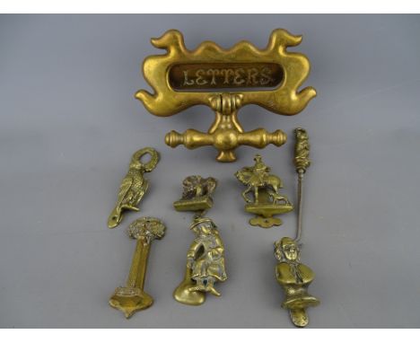 Victorian brass door knocker with letters aperture, six small brass door knockers, various subjects and a brass seated hound 