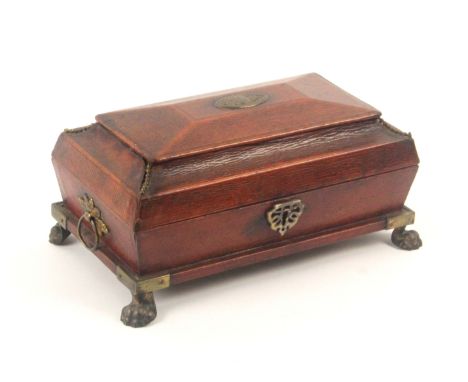 A Regency red leather sewing box, circa 1815, of sarcophagol form raised on brass paw feet, leaf mounted brass ring side hand