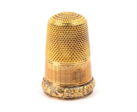 A 19th Century gold thimble, unmarked, the engine turned frieze with vacant rectangular cartouche over a raised border of flo