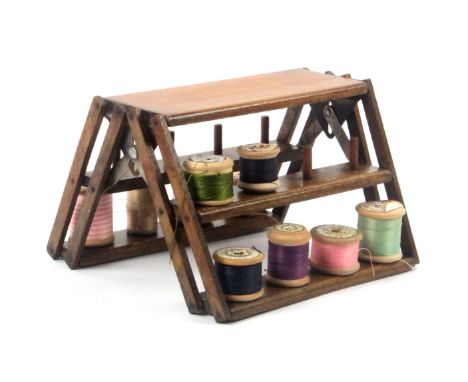 An unusual stained wood reel stand, circa 1920, of folding ladder form, 18cms wide. 
