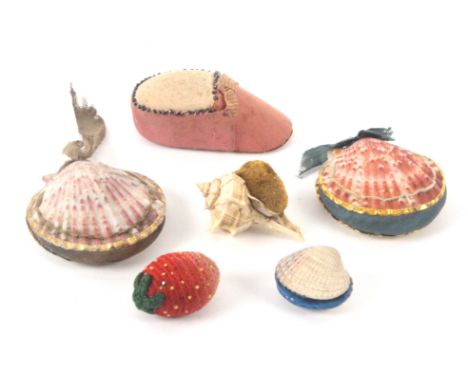 Five pin cushions and an emery, comprising two Georgian examples formed from scallop shells with gilt foil borders, 6cms, two