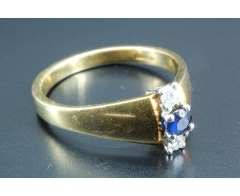 A contemporary diamond and sapphire ring, having a blue sapphire, approximately 0.1 carat, set between two 0.035 carat diamon