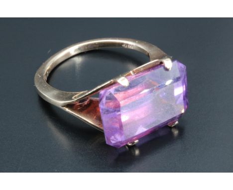 A large and striking amethyst dress ring, the shoulders parting into two panels, upswept to form the setting for an oblong am