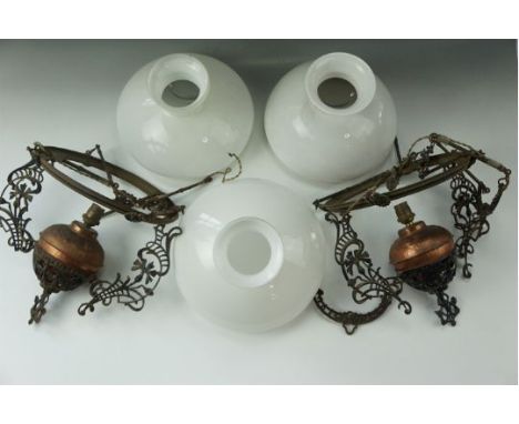 A pair of cast and wrought iron oil lamp pendant lights (later electrified) with glass shades 