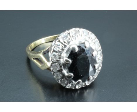 A sapphire and diamond dress ring, having an oval blue sapphire, 9 x 7 mm, surrounded by 16 small round diamonds, approximate