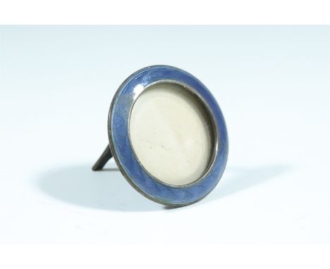 An uncommonly small basse taille enamelled Sterling standard white metal photograph frame, circular and blue enamelled over a