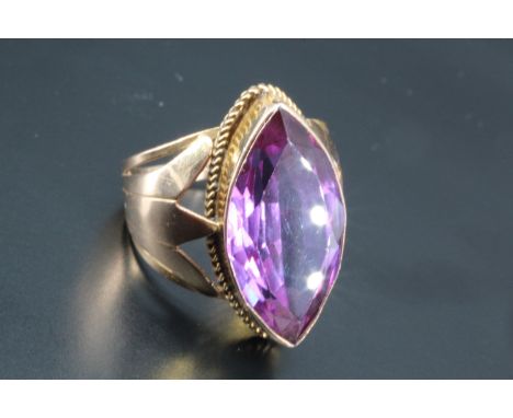 An Egyptian purple sapphire ring, comprising a large marquise cut stone of approx 25 mm x 10 mm / 14 ct rub-set in a deep col