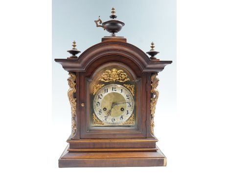 An Early 20th Century German walnut mantle clock, having a broken arch dial with Arabic numerals and striking on two gongs, t