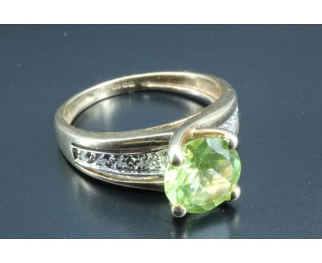 A green semi-precious gemstone solitaire ring, the 8 mm round green brilliant cut stone set between the terminals of the upsw