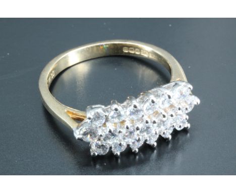 A lady's 14 carat gold cluster set dress ring, having a line of five 2 mm diameter cubic zirconias, set above a surrounding b