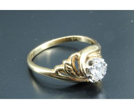 A diamond solitaire ring, having a 0.15 carat diamond, illusion set in a white metal crown, the tapering shoulders winding ar