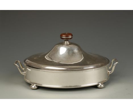 A BREAKFAST DISH AND COVER of oval form, the pull-off cover with wooden disc finial, "D"-shaped carrying handles, the whole o