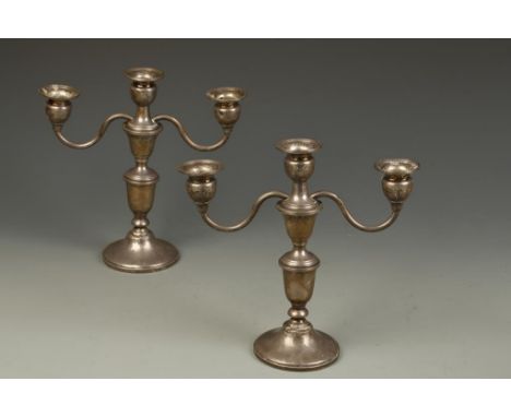 A PAIR OF THREE LIGHT CANDELABRA with waisted cylindrical stems, on filled circular bases, each marked "Sterling", 9" high