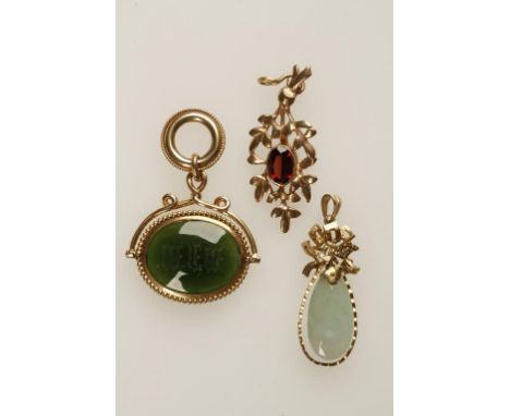 A JADE PENDANT, the pear-shaped jade suspended in an openwork 14k yellow gold frame, and two other gold pendants, one of flor
