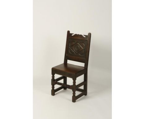 AN OAK PANELLED BACK SIDE CHAIR, with carved back and solid seat, above a turned stretcher, 17th century and later, 40" high.