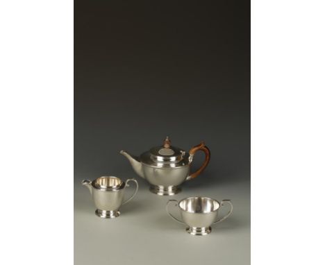 A THREE PIECE TEA SET of circular tapering form, the teapot with wooden scroll handle and finial, on a tucked-in circular foo