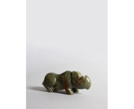 A dark green jade rhinoceros, with detailed scrolled and linear decorations over the body and sides of the head and ears. The