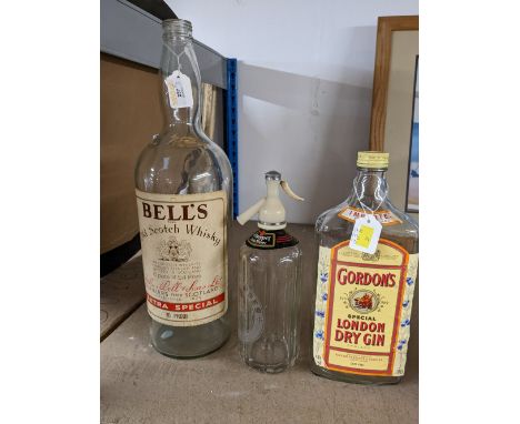 Large empty Bells Scotch Whisky bottle with Schweppes soda water dispenser and Gordon's Gin bottle 