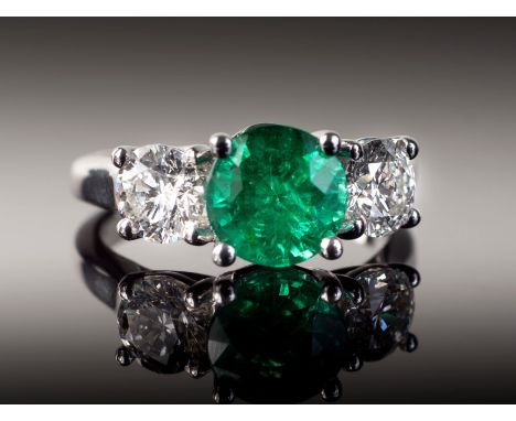 An 18ct white gold, Zambian emerald and diamond three stone ring, the central round cut 1.60ct emerald of fine colour and goo