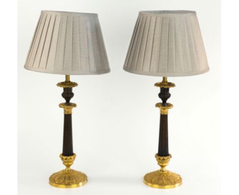 A pair of French patinated bronze and ormolu candlesticks, second half of 19th century, the foliate urn sconces on patinated 