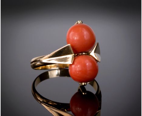 A vintage yellow gold and coral ring, 1950s-60s, the two 8mm. coral beads within chamfered arrow shaped shoulders, ring size 