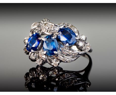 A vintage 18ct white gold, sapphire and diamond ring, 1950s-60s, the three oval cut sapphires of good colour, within a foliat