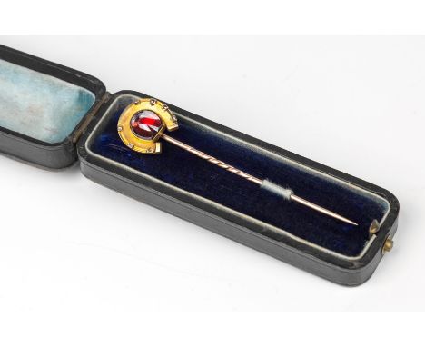 An Edwardian rose and yellow gold, garnet and diamond horseshoe stick pin, the matted yellow gold horseshoe centre with a sha
