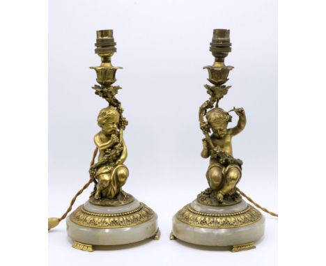 A pair of French ormolu gilt bronze cherub candlesticks, late 19th early 20th century, the cherubs intangled amidst grape vin