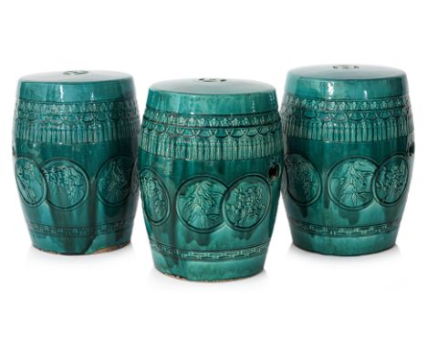 A SET OF THREE GREEN GLAZED BARREL FORM CERAMIC STOOLS
Decorated in relief with roundels of assorted flowers and foliage, twi