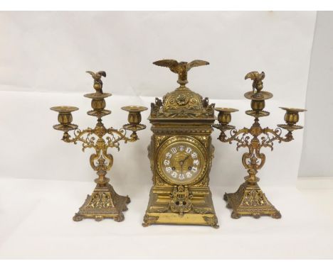 Late Victorian brass garniture comprising a clock with eagle finial 38cm high, and a pair of three-light candalabra 36cm high