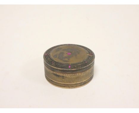 French silver engine turned cylindrical pill box, the lid with central inset ruby encircled by a stylised floral border with 
