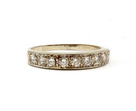 An 18ct white gold diamond half eternity ring, with a row of brilliant cut diamonds, grain set, to tapered shoulders and a fl