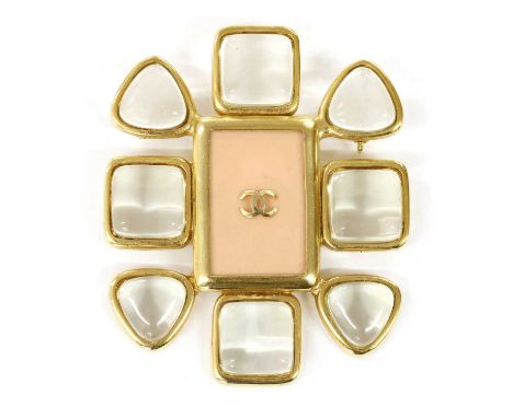 A Chanel gold-plated brooch, with the Chanel logo to the centre of a coral-coloured plaque, with a border of rub set colourle