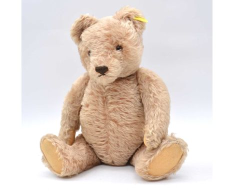 Steiff teddy bear, 1950s, with growler, hump back, brown glass eyes, yellow with silver button, jointed limbs, 42cm.