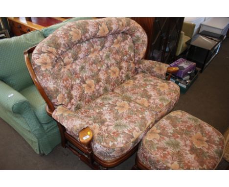 An Ercol style floral upholstered two seater settee with matching foot stool