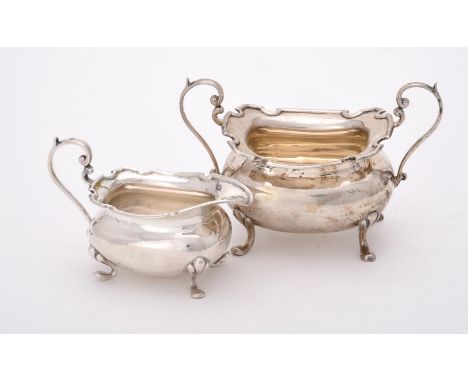 
	
		A silver oblong baluster cream jug and sugar basin by Walker &amp; Hall, Sheffield 1910, the sugar basin with twin scrol