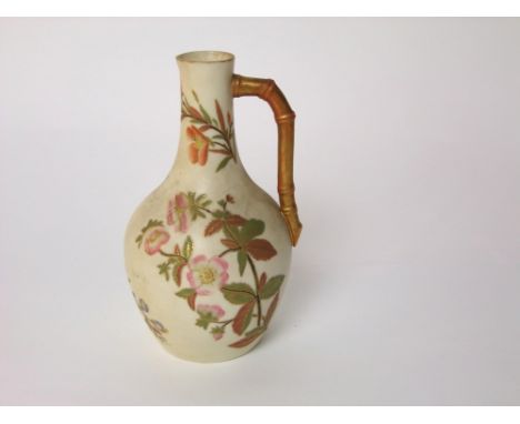 A Royal Worcester ivory ground jug with painted and gilded floral decoration and simulated gilded bamboo handle with puce pri