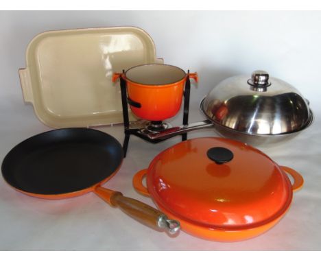 A collection of Le Crueset to include a twin handled flat based dish, a further casserole dish, enamel frying pan, fondue pan