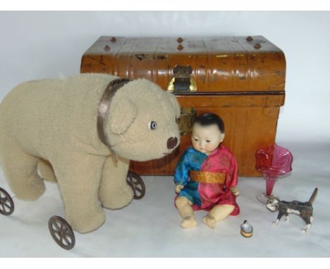 A tin trunk containing a collection of various vintage toys to include a polar bear on a trolley and a bisque head German dol