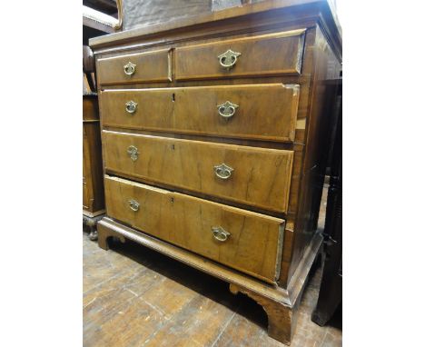 A Georgian walnut veneered bedroom chest of three long and two short graduated oak lined drawers raised on bracket supports, 