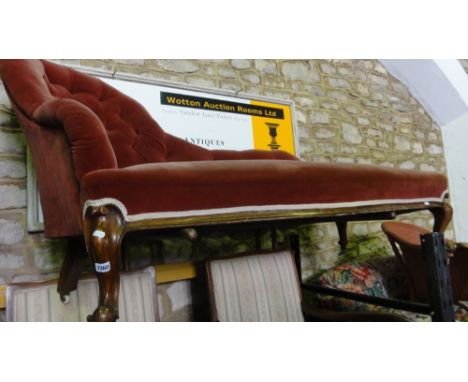 A Victorian mahogany chaise lounge with button back red upholstery, scrolled front legs and ceramic castors