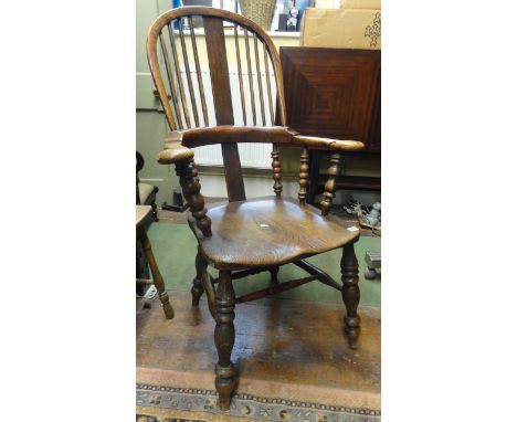 An early 19th century Windsor comb back elbow chair with turned spindle mouldings and supports, principally in elm and ashwoo