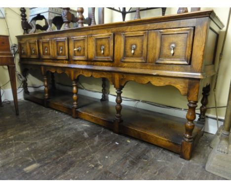 A good quality Jacobean style oak pot board dresser enclosing four frieze drawers each disguised as two, raised on seven turn