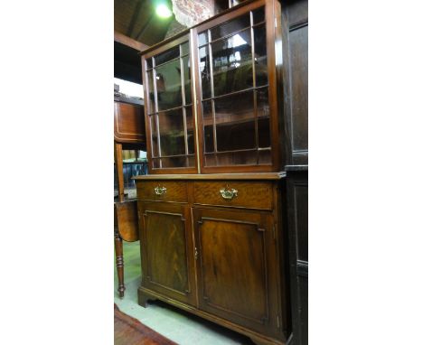 A mahogany and figured mahogany bookcase on stand, the glazed top enclosing a shelved interior upon a base fitted with two sh