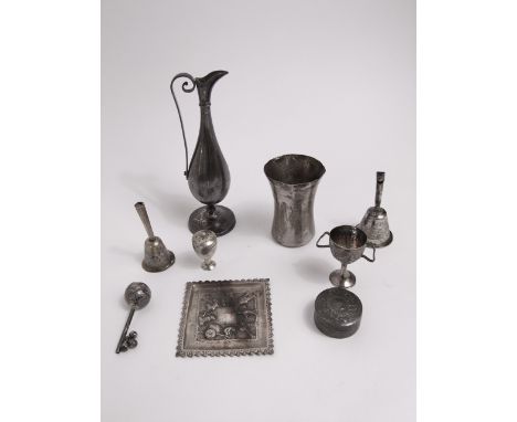 A collection of Indian white metal items to include two bells with integrated whistles, a small square dish, a baby rattle, a