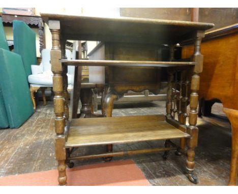 An Arts & Crafts oak three tier occasional table of rectangular form with turned bobbin supports and ball and rod grid panels